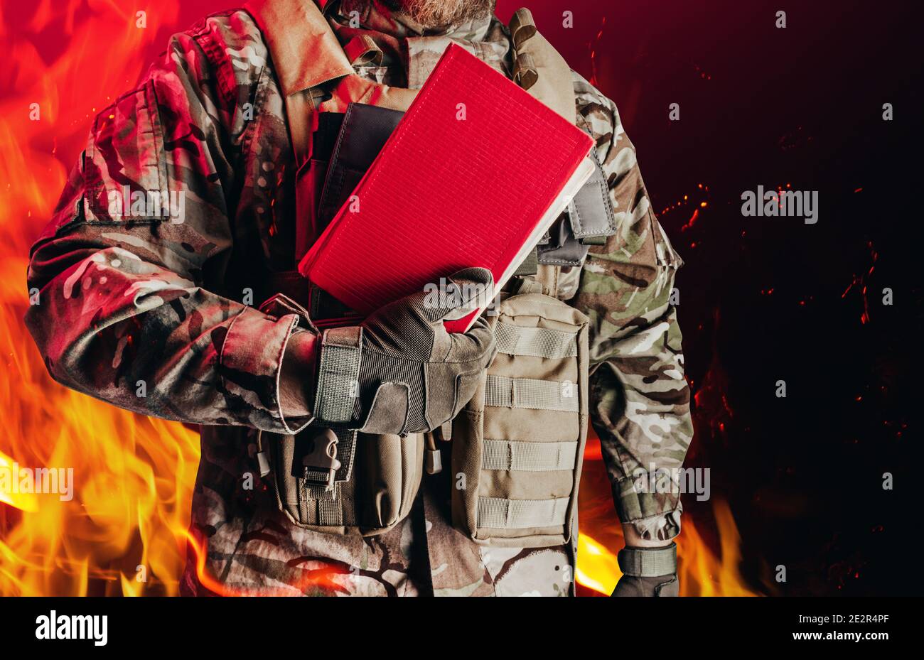 Foto di un soldato in uniforme che tiene chiuso libro rosso su sfondo fiamma  ardente Foto stock - Alamy
