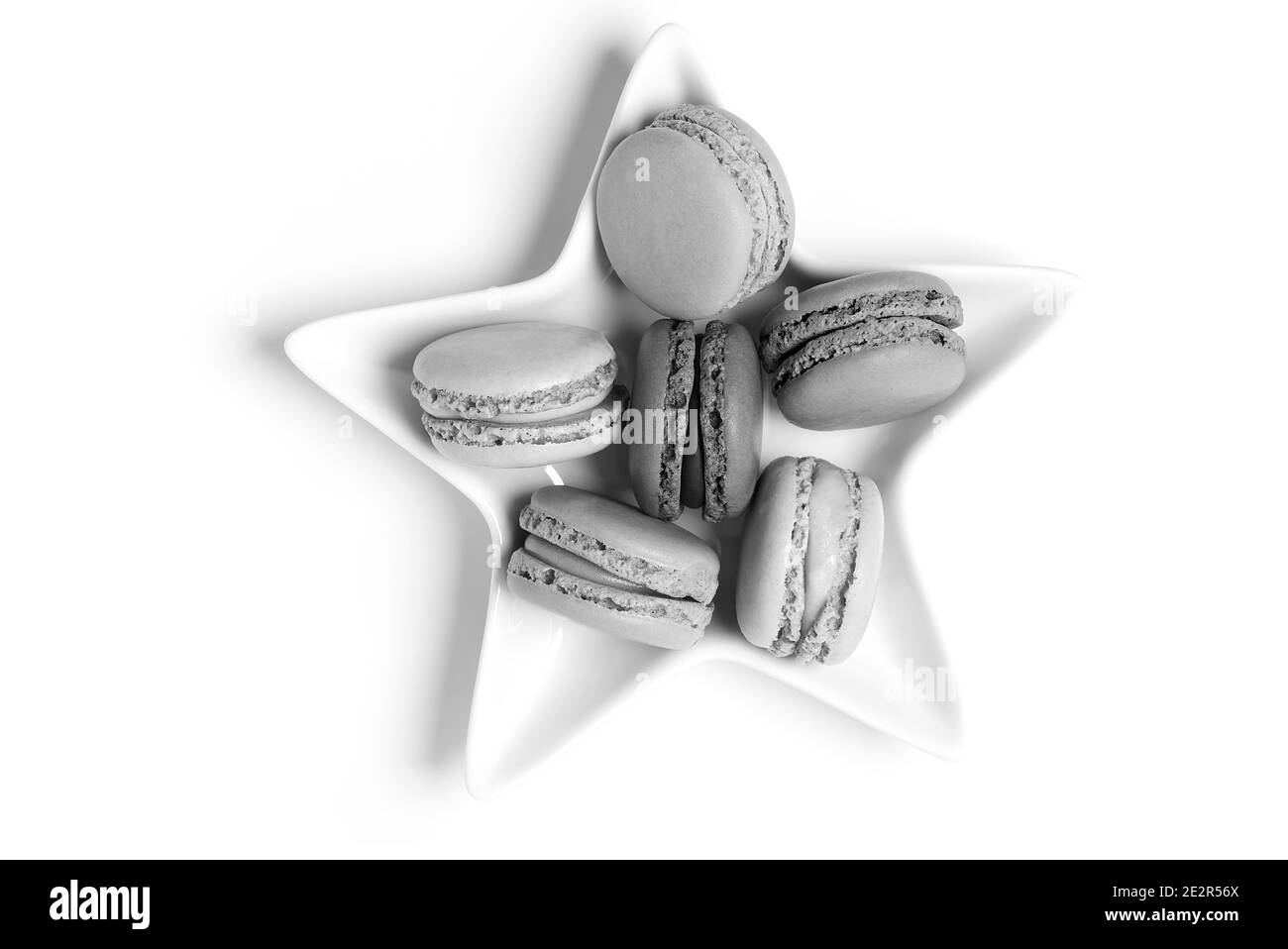 Piccoli macaron dolci colorati in bianco e nero su stella piatto su sfondo bianco Foto Stock