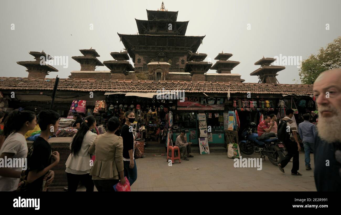 Il traffico di fronte ad una fila di negozi di strada in Piazza Durbar di Kathmandu, con il Tempio di Taleju può essere visto sullo sfondo. Kathmandu, Nepal. Foto Stock