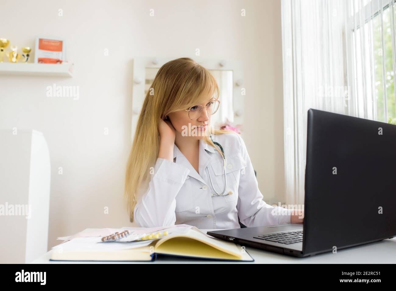 Consulenza medica online in ufficio. Medico giovane che lavora su un computer portatile. Parla e tratta la distanza. Conversazione con il paziente web. Foto Stock