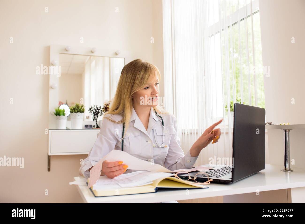 Consulenza medica online in ufficio. Medico giovane che lavora su un computer portatile. Parla e tratta la distanza. Conversazione con il paziente web. Foto Stock
