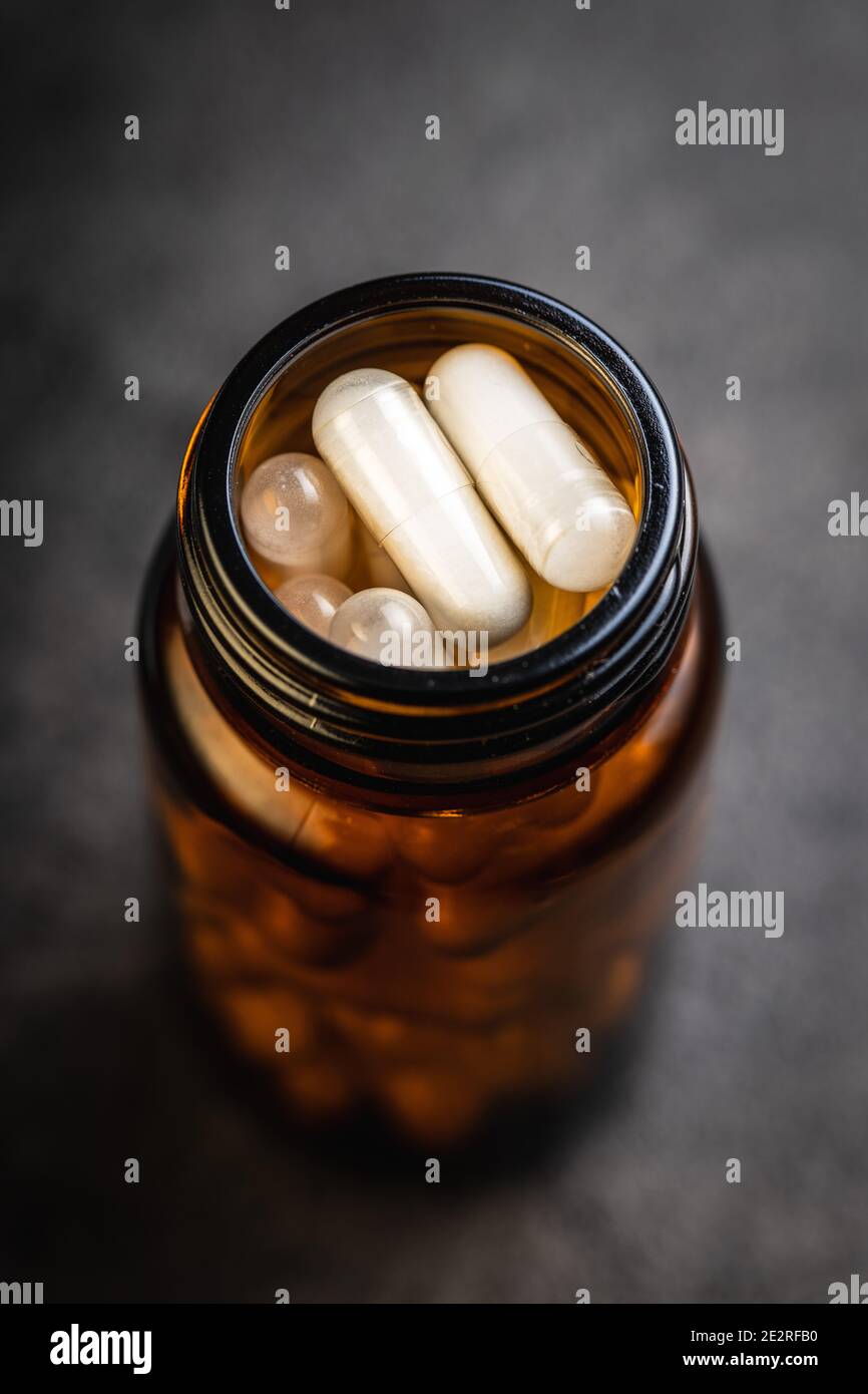 Pillole mediche bianche in contenitore. Pillole, compresse e capsule di medicina farmaceutica in vaso di vetro. Foto Stock
