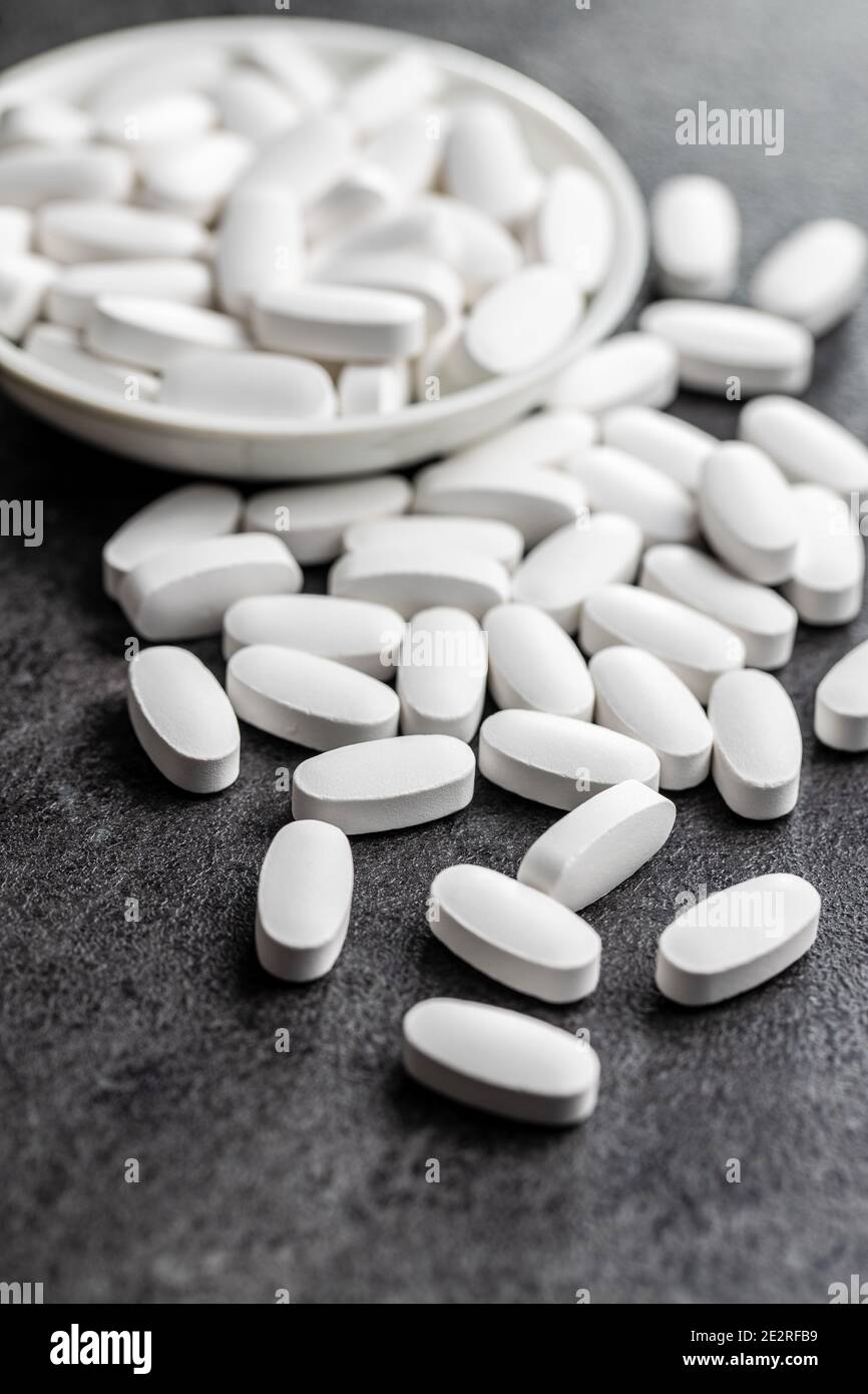 Pillole mediche bianche. Pillole, compresse e capsule di medicina farmaceutica su tavola nera. Foto Stock