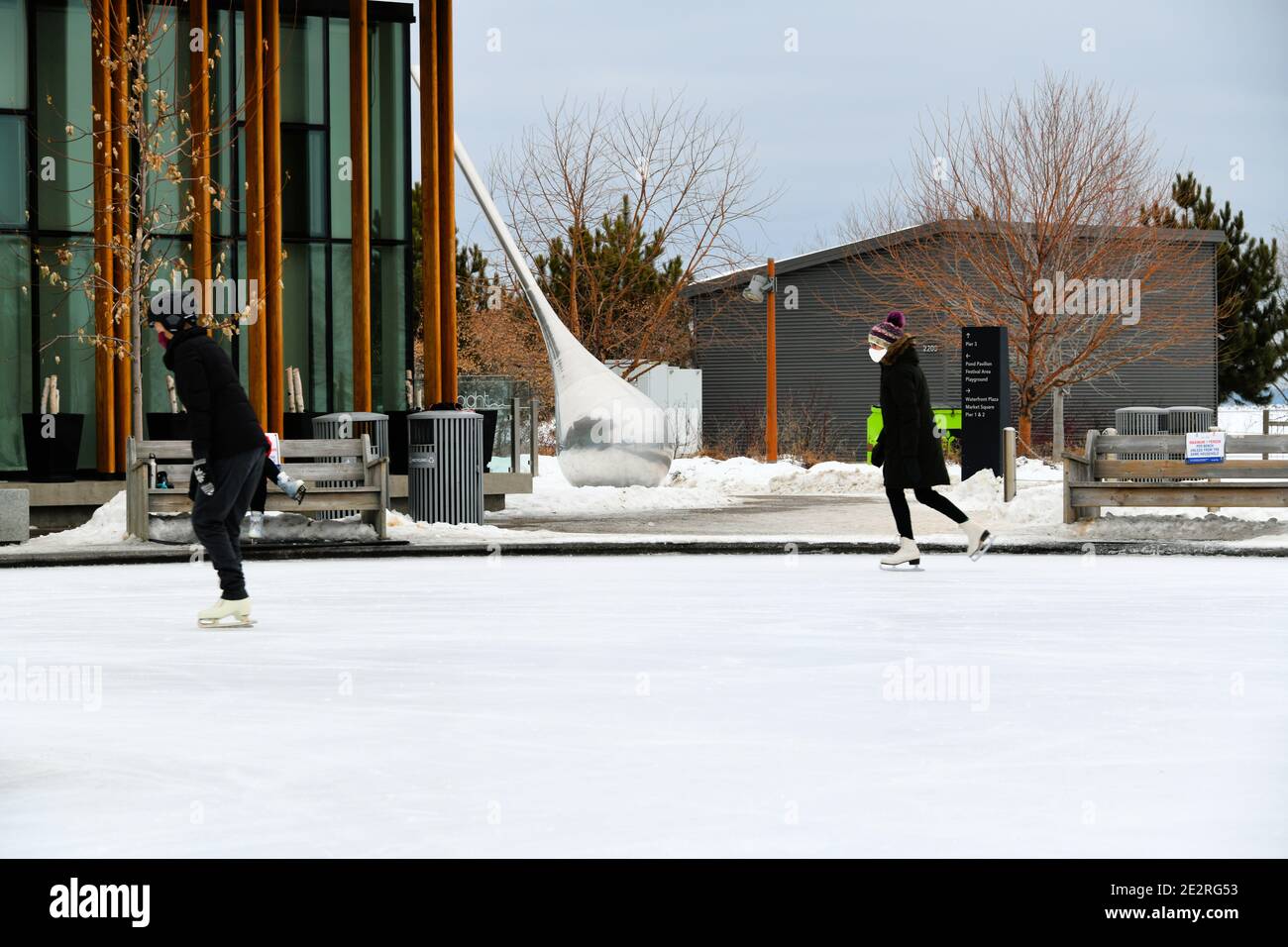 Due donne che pattinano sulla pista di pattinaggio all'aperto al Marina Park di Thunder Bay, Canada, mantenendo una distanza adeguata durante la pandemia del covid-19. Foto Stock