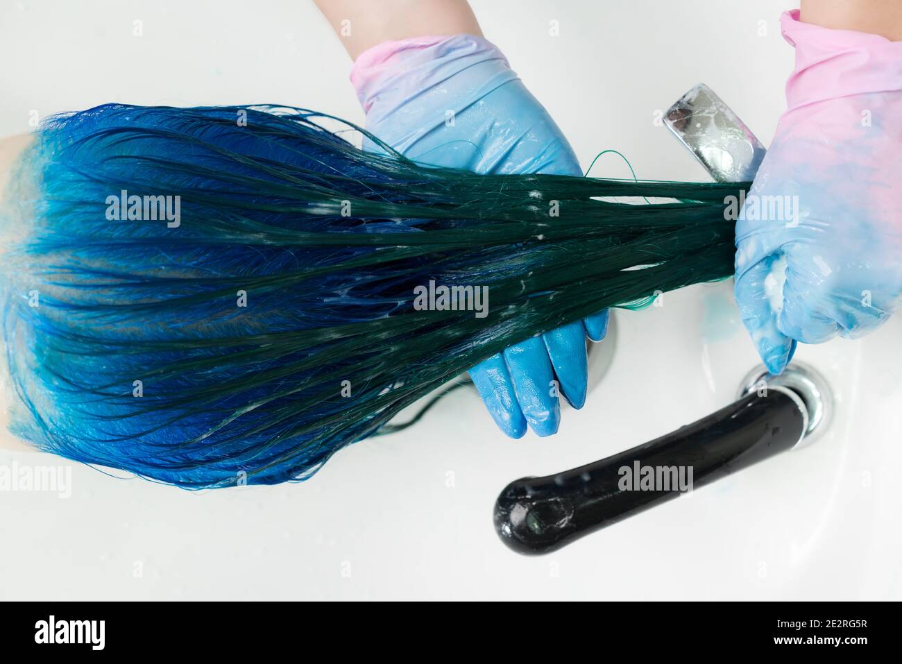 Vista dall'alto del parrucchiere in guanti lavano la testa del cliente con  capelli lunghi colore