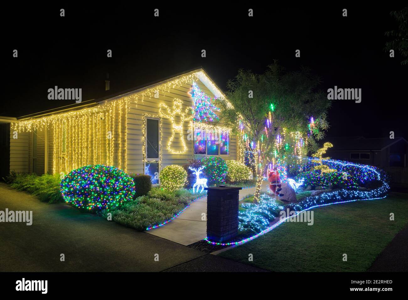 Una casa suburbana e giardino di notte, splendidamente illuminato con luci di Natale Foto Stock