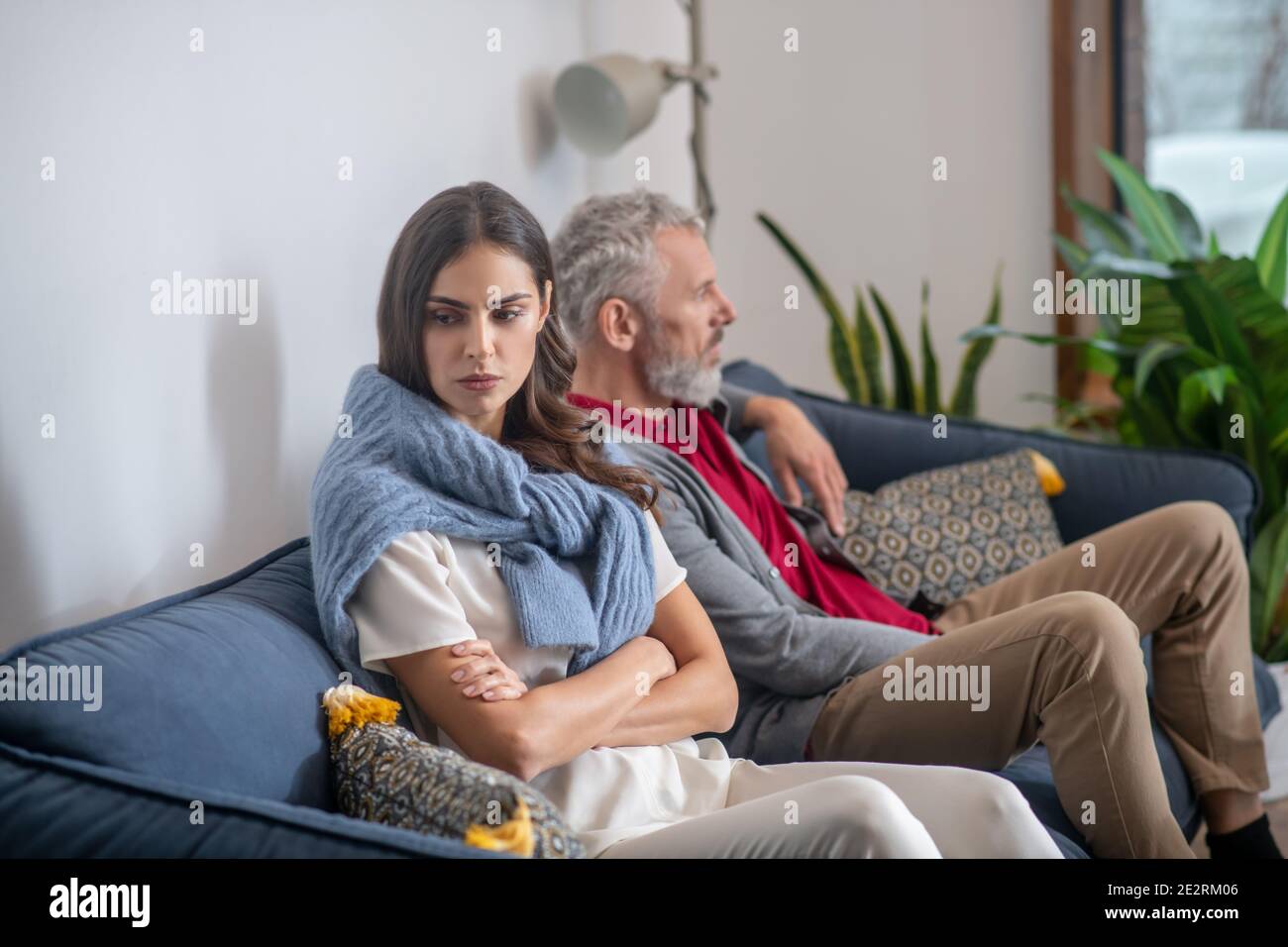 Giovane donna e uomo sopportato seduto su un divano Foto Stock