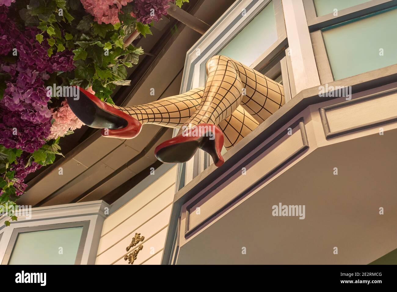 Gambe appese fuori finestra con calze a rete e scarpe a stiletto rosso che pubblicizzano un negozio di abbigliamento femminile. Thailandia Sud-est asiatico Foto Stock