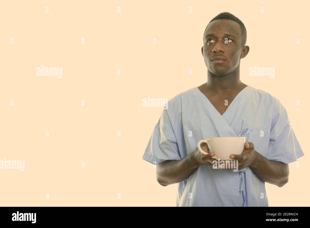 Studio shot del giovane africano nero Uomo di pensiero del paziente tenendo tazza da caffè Foto Stock