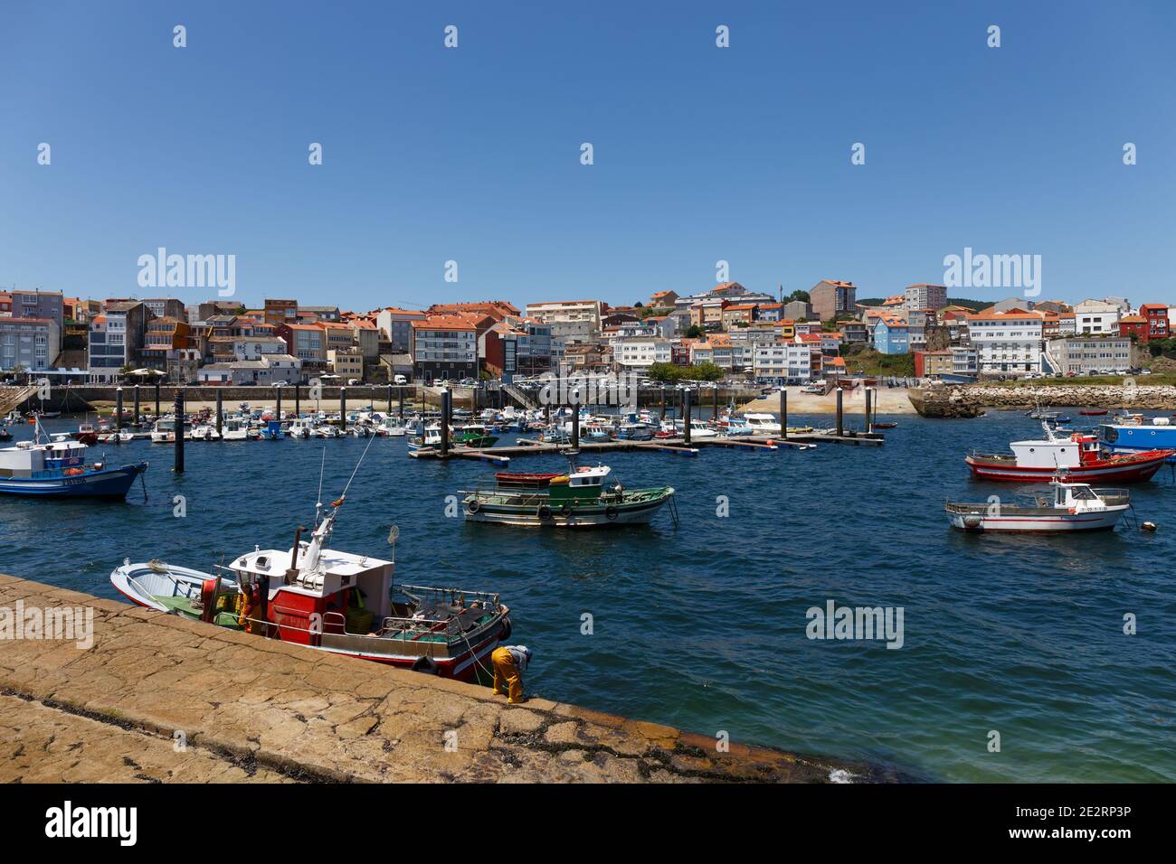 Barche da pesca e due pescatori, con vista sulla città sullo sfondo in una giornata di sole, Finisterre, Galizia, Spagna Foto Stock