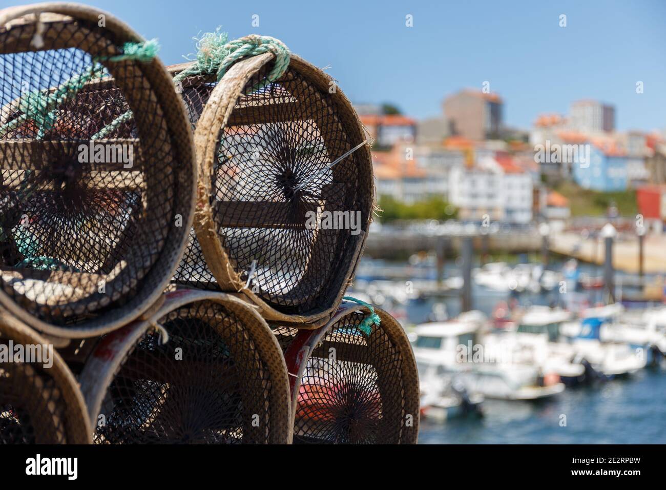 Pentole per la pesca del granchio e dell'aragosta accatastate con vista sulla città sullo sfondo, Finisterre, Galizia, Spagna Foto Stock