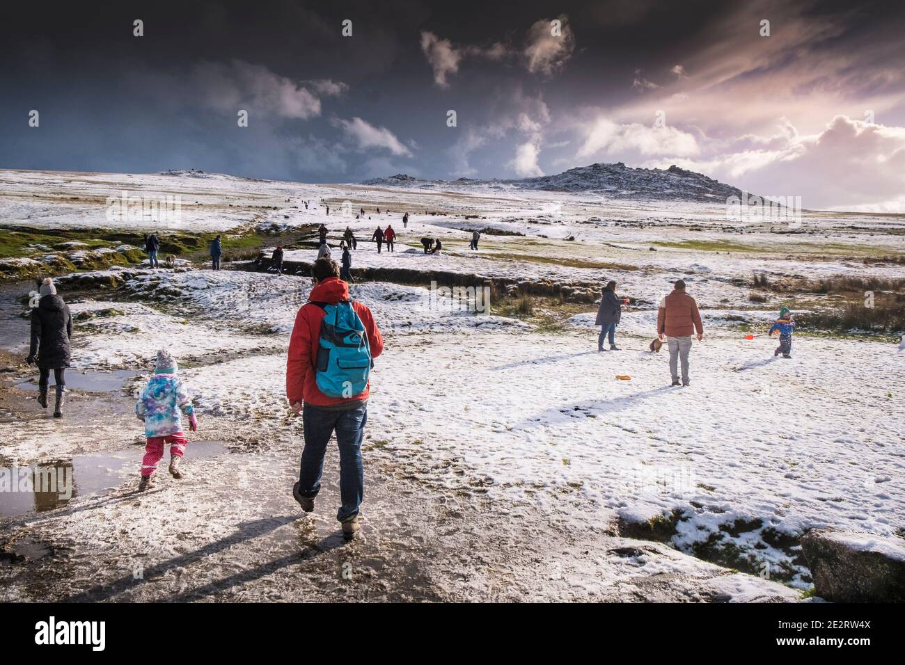 Le persone che si divertiscono a camminare nella neve sul selvaggio e aspro Rough Tor su Bodmin Moor in Cornovaglia. Foto Stock