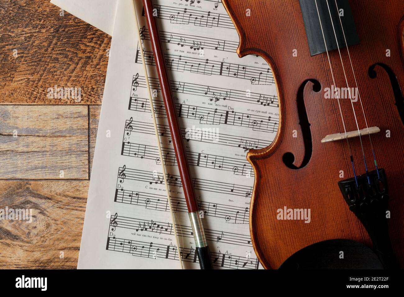 Violino, note musicali e piatto di prua su sfondo ligneo. Ombre morbide. Foto Stock