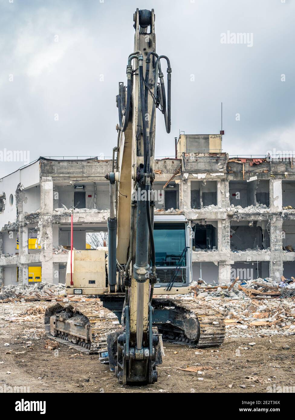 Escavatore in loco vicino a un edificio demolito Foto Stock