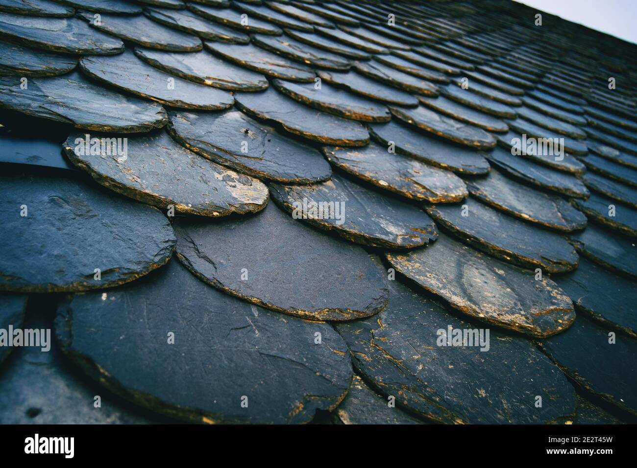 tetto con vecchie piastrelle di colore scuro, tra nero e grigio. Creare una ripetizione con texture da una prospettiva angolata Foto Stock