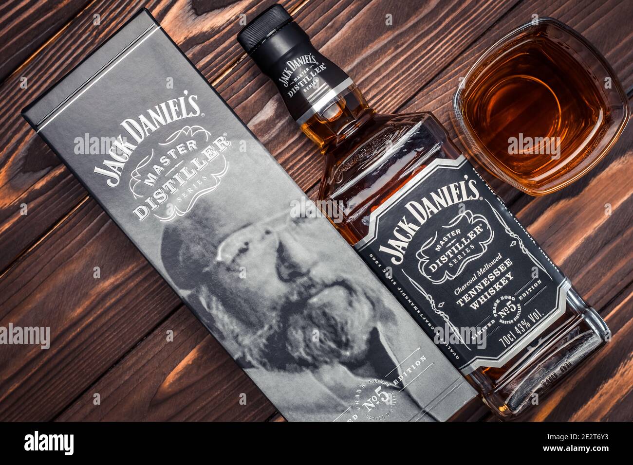 Kharkiv, Ucraina, 14 gennaio 2021: Bottiglia completa e bicchiere di whiskey americano Jack Daniel 5 su tavole di legno marrone scuro. Bevanda forte. I vecchi dieci Foto Stock