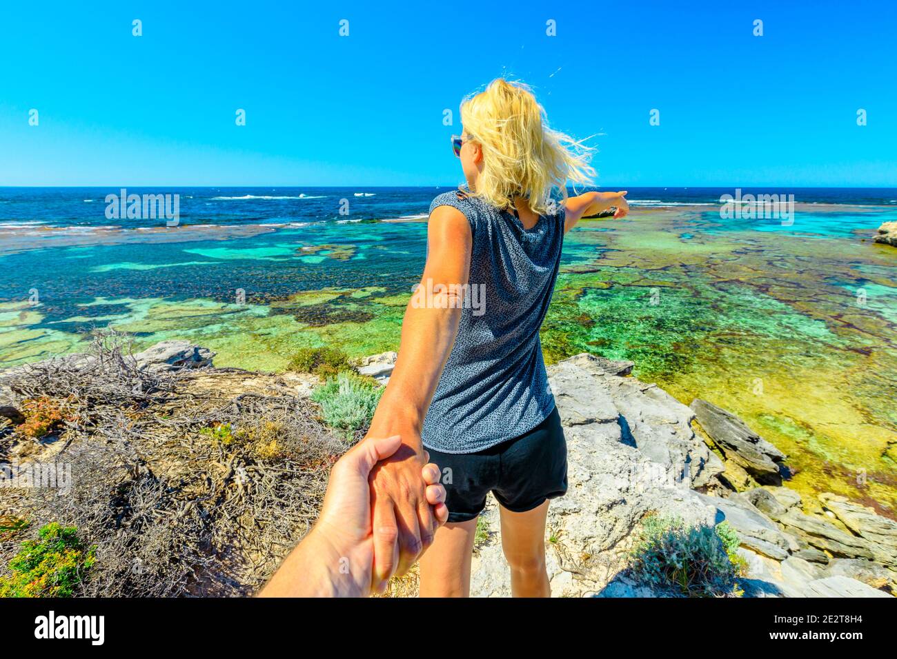 Seguimi, ragazza che tiene la mano sopra promontorio di Jeannies Lookout a Rottnest Island, Australia occidentale. Turismo a Perth, Australia. Concetto di Foto Stock