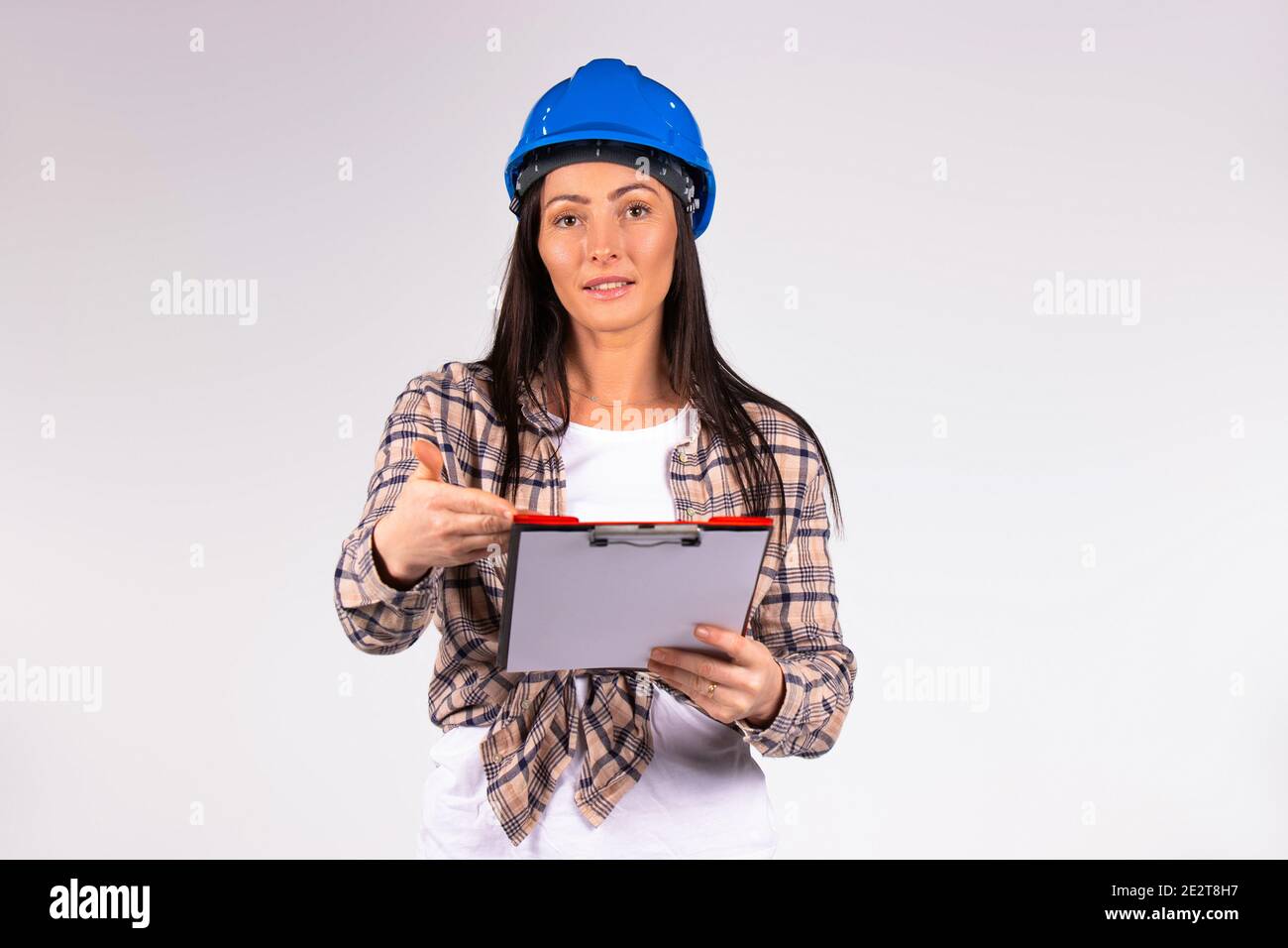 Donna ingegnere con piegatrice in posa e sorridente alla fotocamera. Sfondo grigio con spazio laterale per la pubblicità. Foto Stock