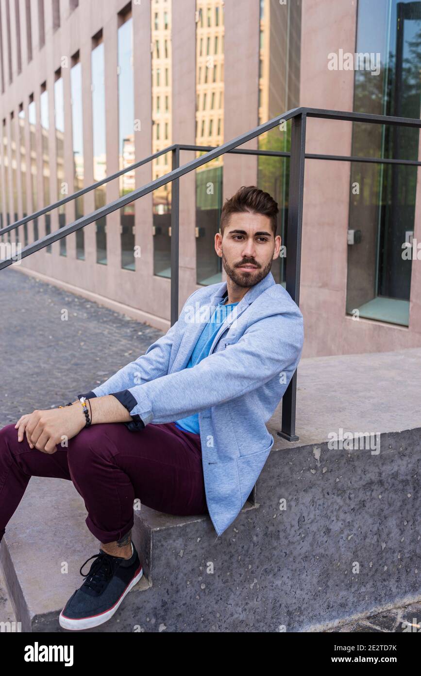Felice ragazzo sopportato seduto sui gradini Foto Stock