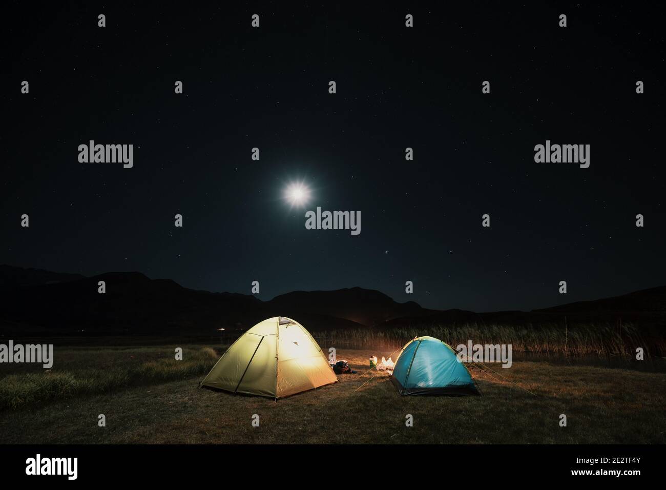 Campeggio in montagna sotto la luna. Una tenda si accampò e si illuminò sotto il cielo. Foto Stock