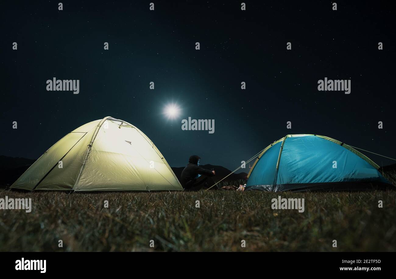 Campeggio in montagna sotto la luna. Una tenda si accampò e si illuminò sotto il cielo. Foto Stock