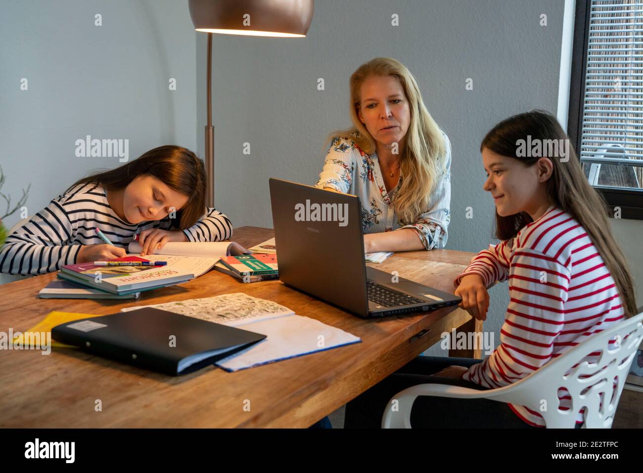 Homeschooling, durante il blocco nel gennaio 2021, madre aiuta le sue due figlie, a casa, ad imparare, con libri di testo e computer, la chiusura della scuola, Foto Stock