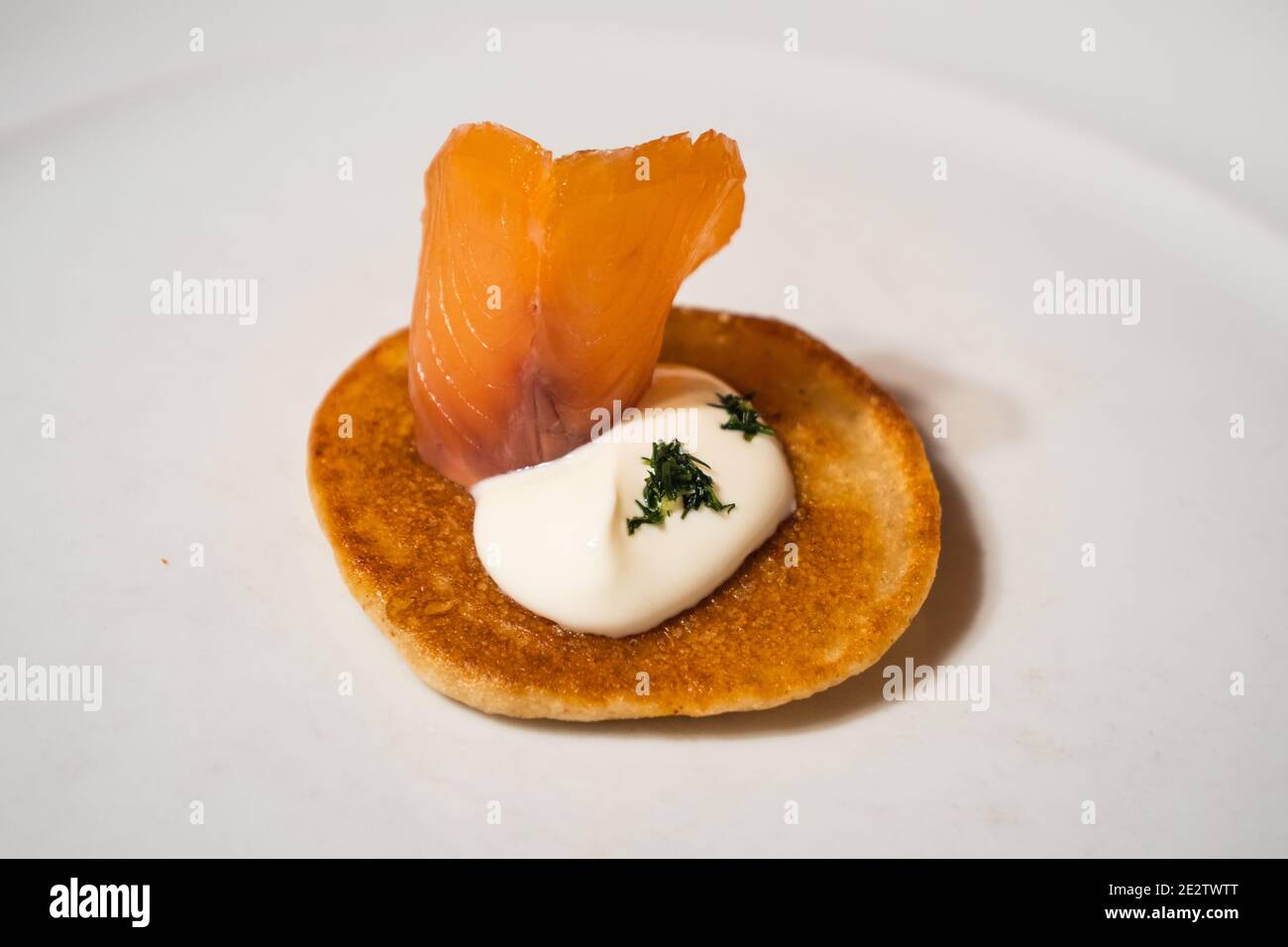 Salmone affumicato Blini guarnito con panna acida e aneto Una piastra bianca Foto Stock