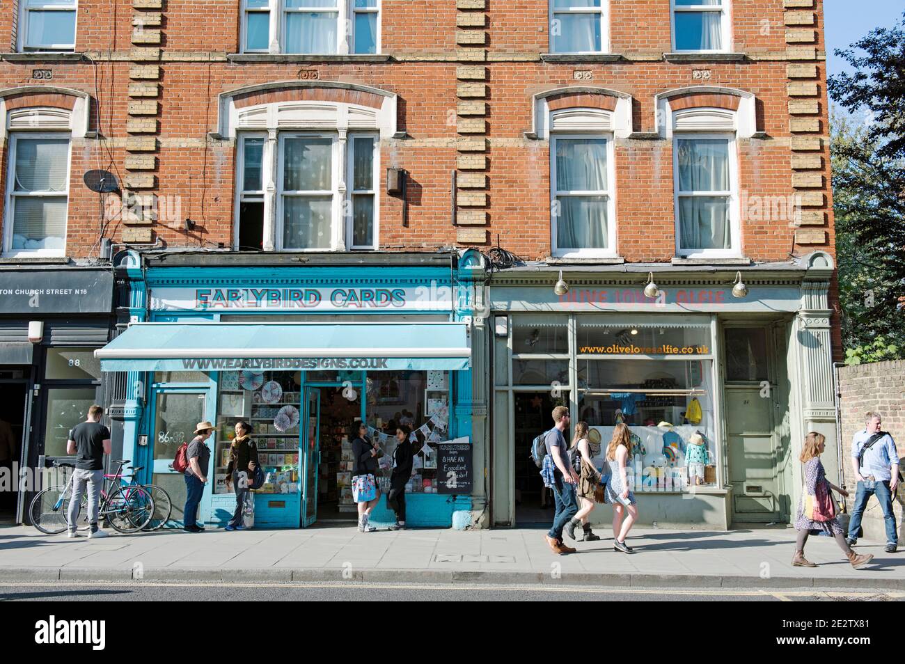 EarlyBird Cards negozio con persone tra cui ciclista che parlano all'esterno e persone che passano. Una trafficata strada urbana Stoke Newington Church Street Londra Foto Stock