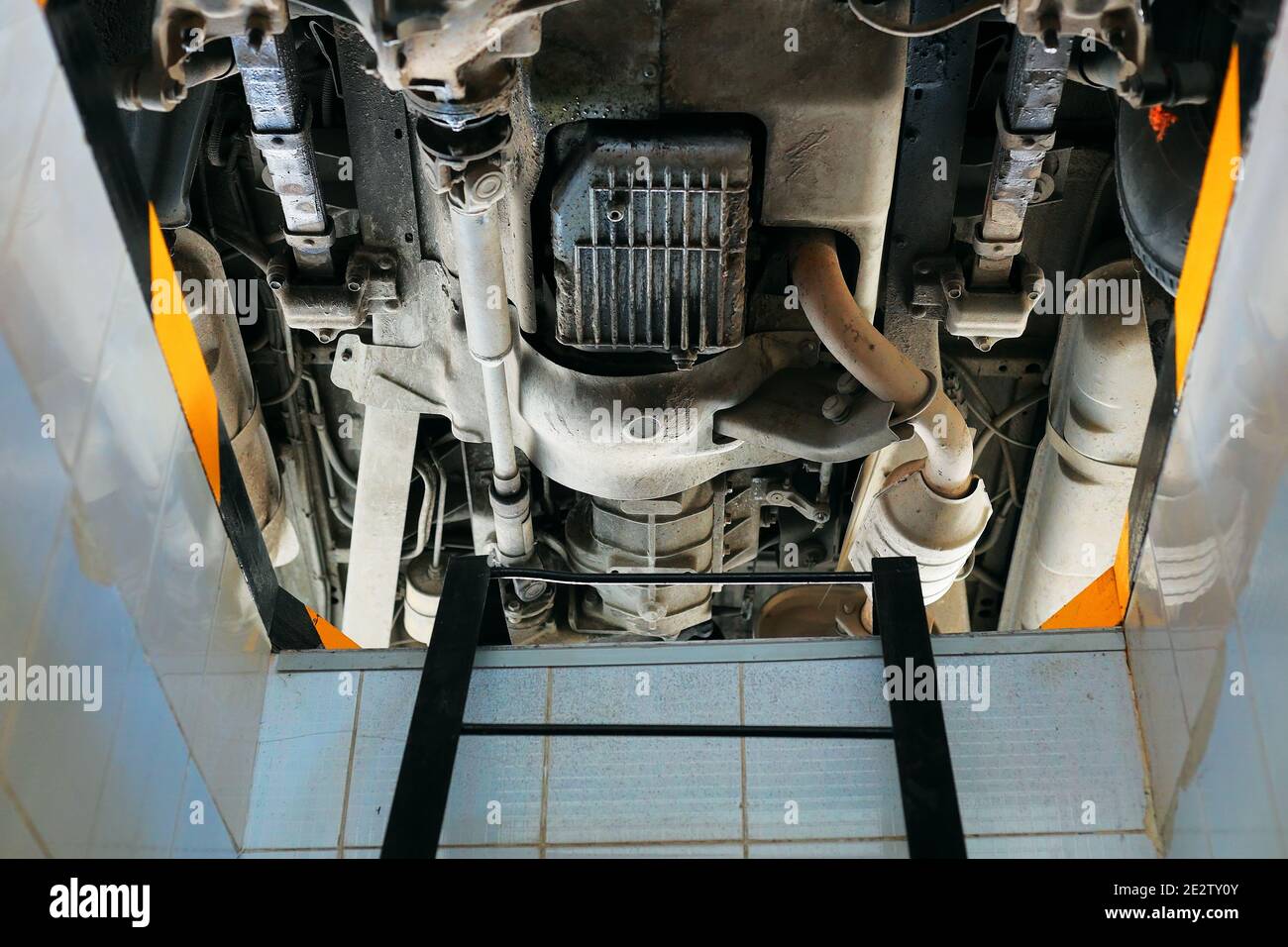 Vista della vettura dalla parte inferiore della fossa di riparazione. Diagnostica e riparazione di un veicolo in un'officina di riparazione automatica. Foto Stock