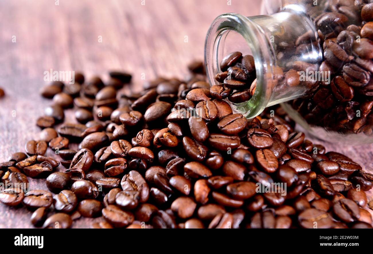 I chicchi di caffè fuoriescono dalla bottiglia di vetro Foto Stock