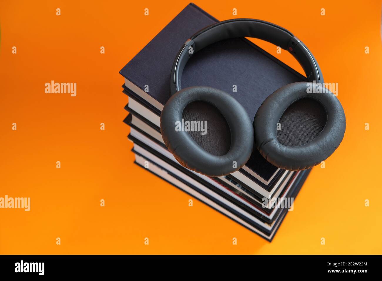 Audiobooks.Reading. Formazione e conoscenza. Formazione a distanza. Una pila di libri e cuffie su uno sfondo arancione luminoso. Audiolibri, e-book e. Foto Stock