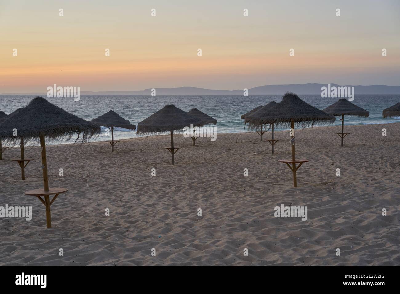 Spiaggia vuota al tramonto a Comporta, Portogallo con ombrelloni estivi di paglia Foto Stock