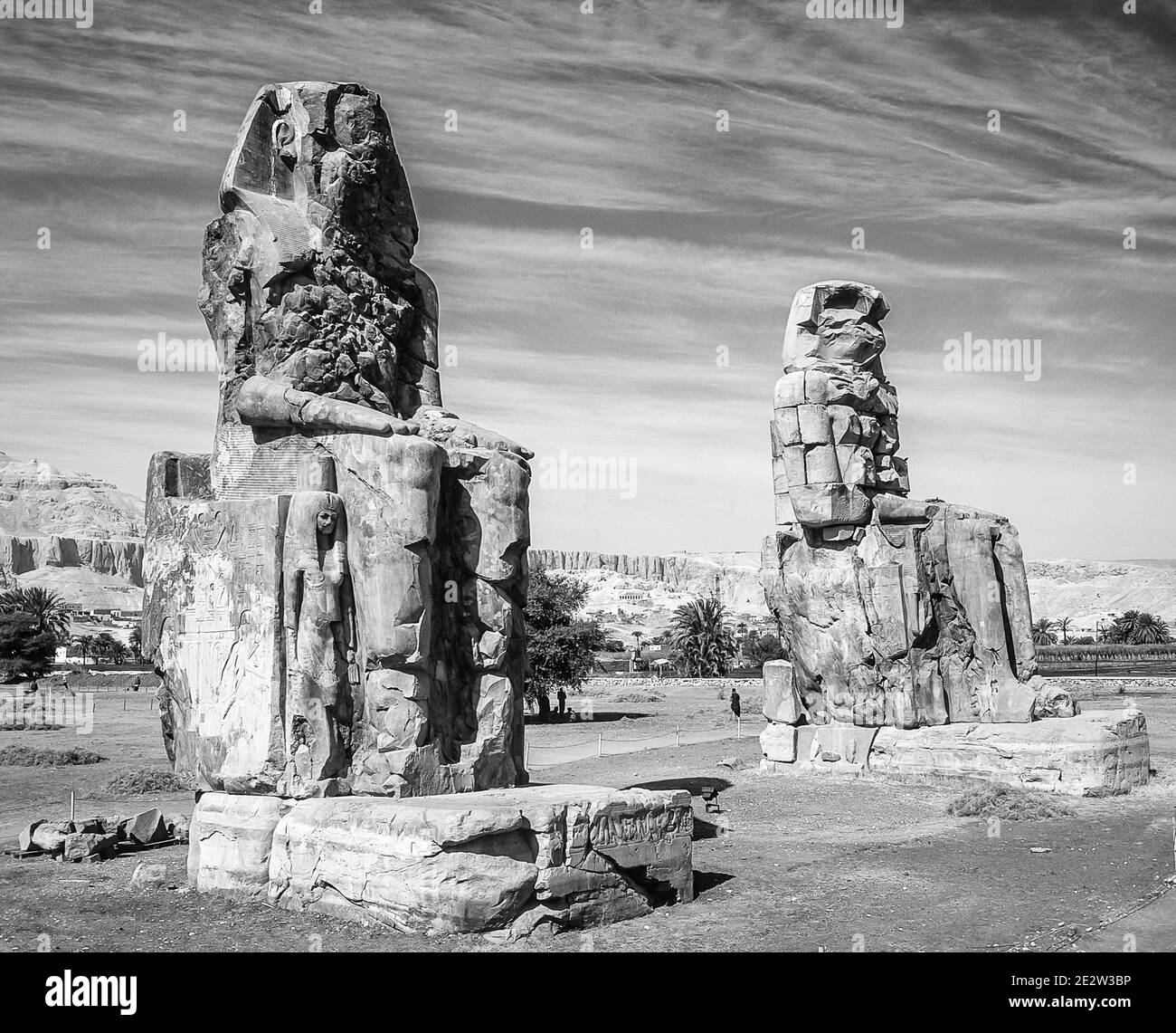 Luxor. Questo è il sito archeologico del 1350 a.C. presso i Colossi di Memnone dell'Antico Egitto, non lontano dal fiume Nilo e dalla città di Luxor precedentemente conosciuta come Tebe. Le statue sono del faraone Amenhotep III, ci sono due statue più piccole ai suoi piedi, una è sua madre, l'altra sua moglie. Inizialmente costruiti per proteggere l'ingresso al tempio di Amenotep contro il male, sono stati anche visti per proteggere la riva occidentale del Nilo. I Colossi hanno sofferto di gravi danni sismici, ma dopo 3500 anni rimangono in piedi. Foto Stock