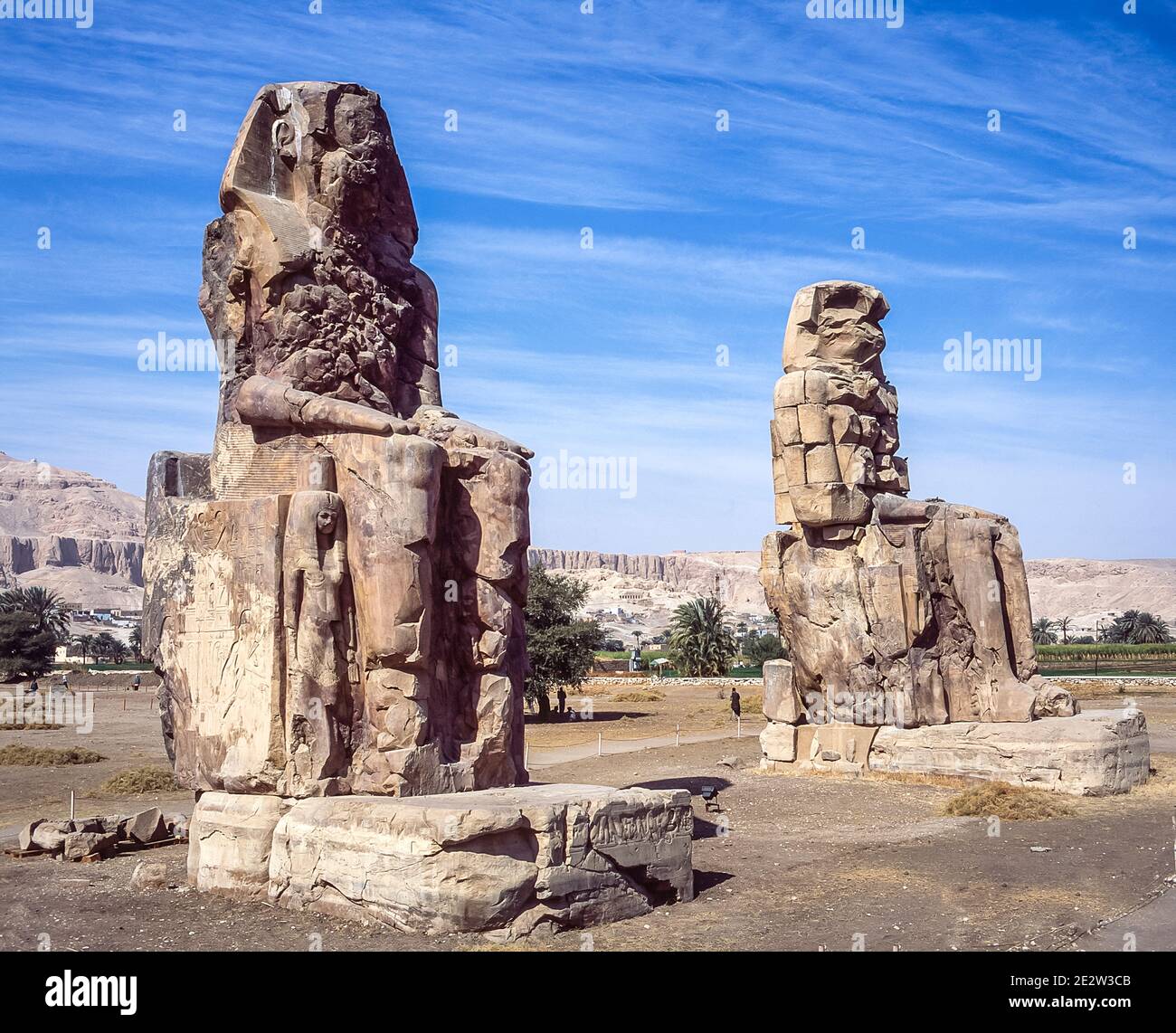 Luxor. Questo è il sito archeologico del 1350 a.C. presso i Colossi di Memnone dell'Antico Egitto, non lontano dal fiume Nilo e dalla città di Luxor precedentemente conosciuta come Tebe. Le statue sono del faraone Amenhotep III, ci sono due statue più piccole ai suoi piedi, una è sua madre, l'altra sua moglie. Inizialmente costruiti per proteggere l'ingresso al tempio di Amenotep contro il male, sono stati anche visti per proteggere la riva occidentale del Nilo. I Colossi hanno sofferto di gravi danni sismici, ma dopo 3500 anni rimangono in piedi. Foto Stock