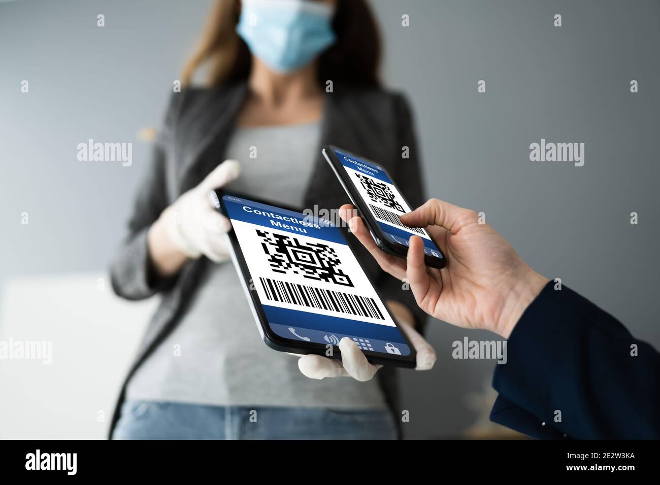 Cliente che esegue la scansione del codice del menu online con lo smartphone che indossa la maschera facciale Foto Stock