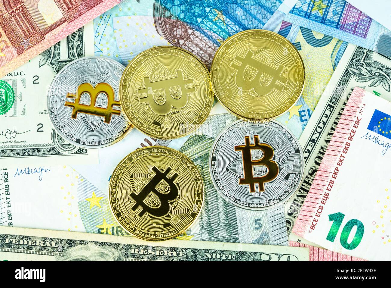 Monete in argento e oro bitcoin su banconote in euro e in dollari. Moderna crittografia digitale in valuta virtuale. Monete metalliche a criptovaluta Foto Stock