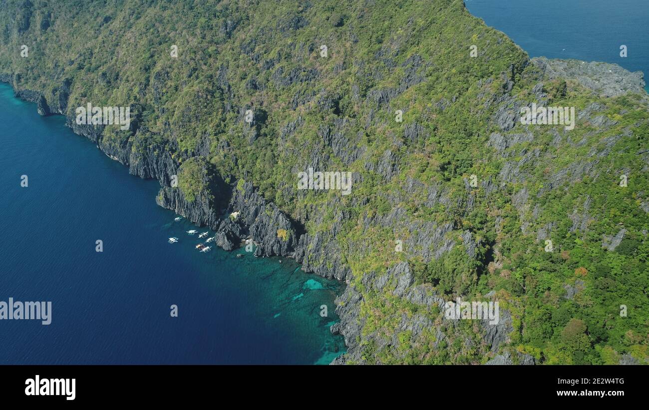 Costa di roccia verde dell'isola di montagna all'antenna dell'acqua della baia dell'oceano. Nessuno mare con natura tropicale di Palawan con barche a scogliera mare riva. Tour estivo in crociera all'isola di El Nido, arcipelago delle Filippine Foto Stock
