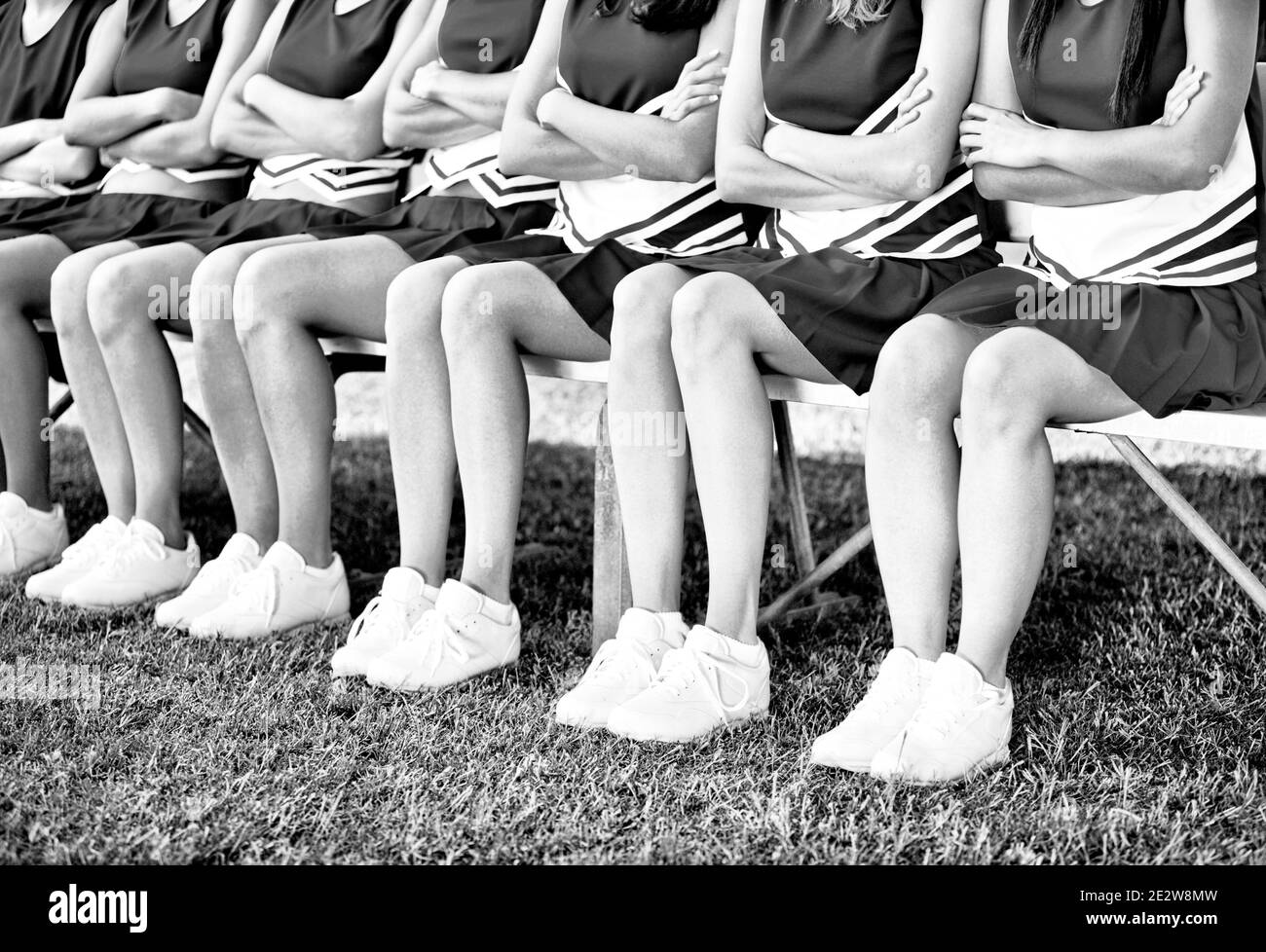 Foto in bianco e nero di cheerleaders seduti sulla panchina Foto Stock