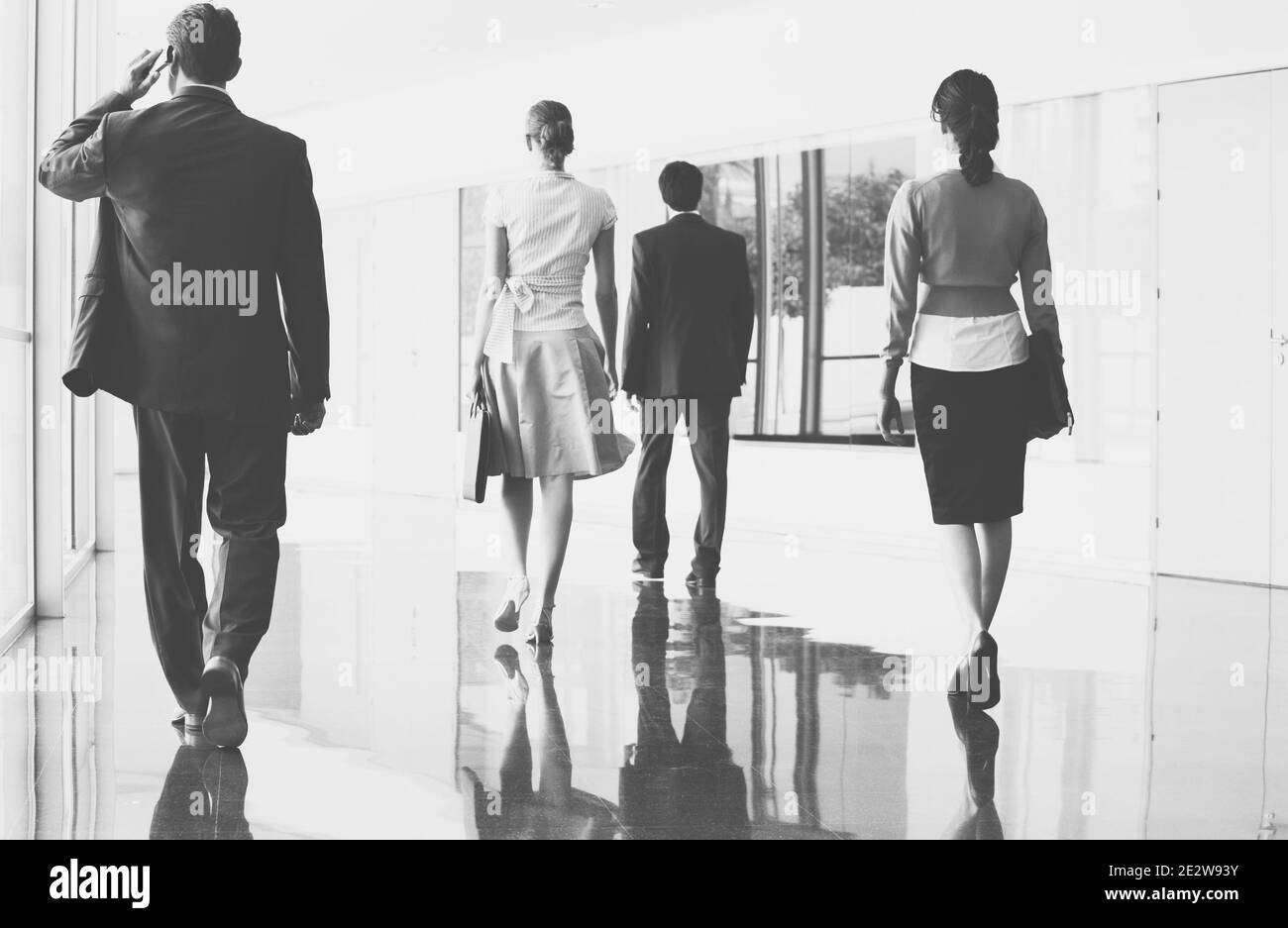 Foto in bianco e nero di uomini d'affari che camminano sul marmo pavimento in ufficio Foto Stock