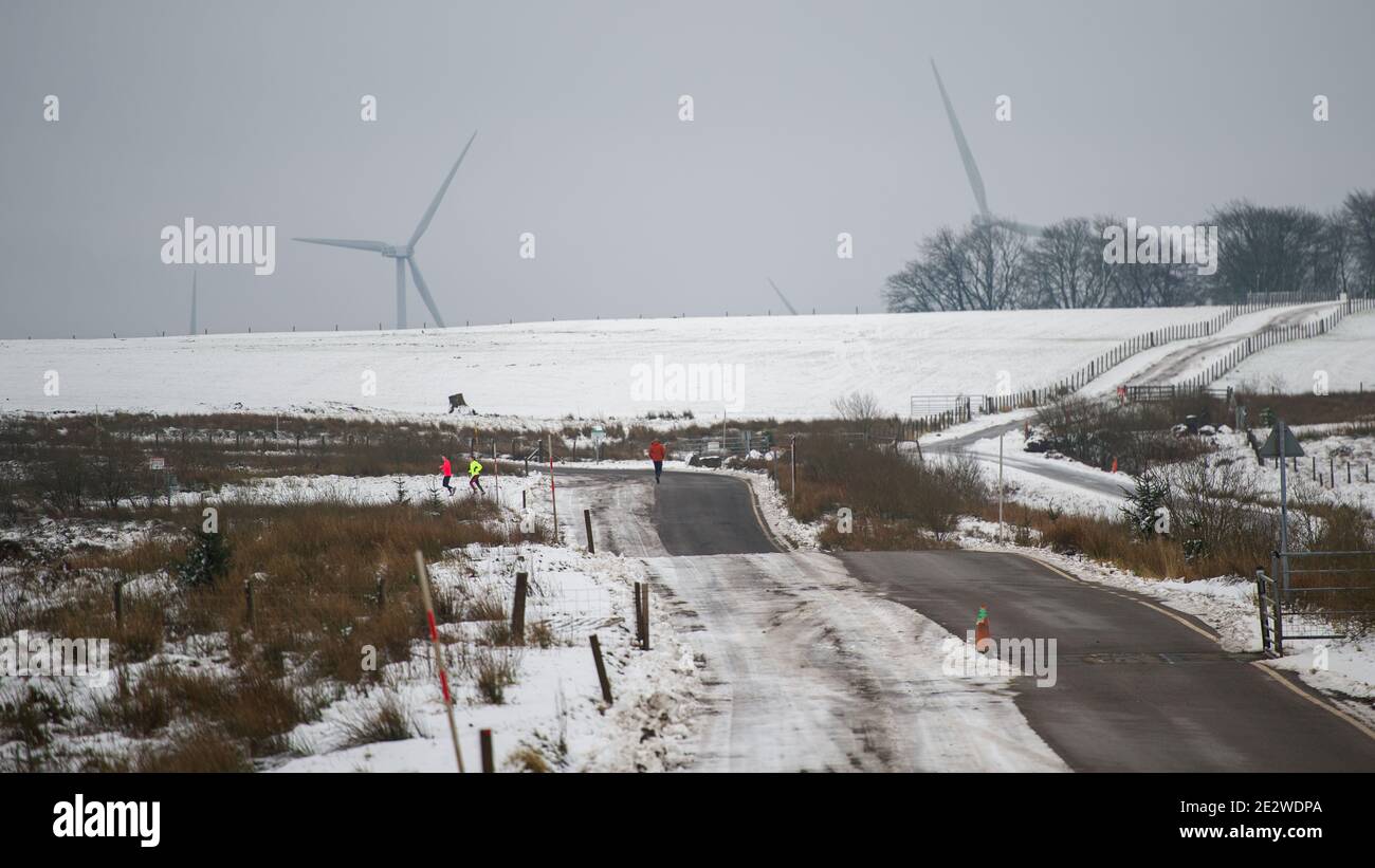 Whitelee Wind Farm, Eaglesham, Scozia, Regno Unito. 15 gennaio 2021. Nella foto: Le persone che camminano e fanno jogging sulla brughiera innevata della Whitelee Wind Farm che si allenano quotidianamente mentre la Scozia è ancora in fase 4 di blocco a causa del Coronavirus (COVID-19) Pandemic. Whitelee Wind Farm visto sotto un tappeto di neve, che è ancora steso sul terreno a causa della sua posizione sul terreno più alto. È popolare con la gente che prende il loro esercizio quotidiano di blocco. Credit: Colin Fisher/Alamy Live News Foto Stock