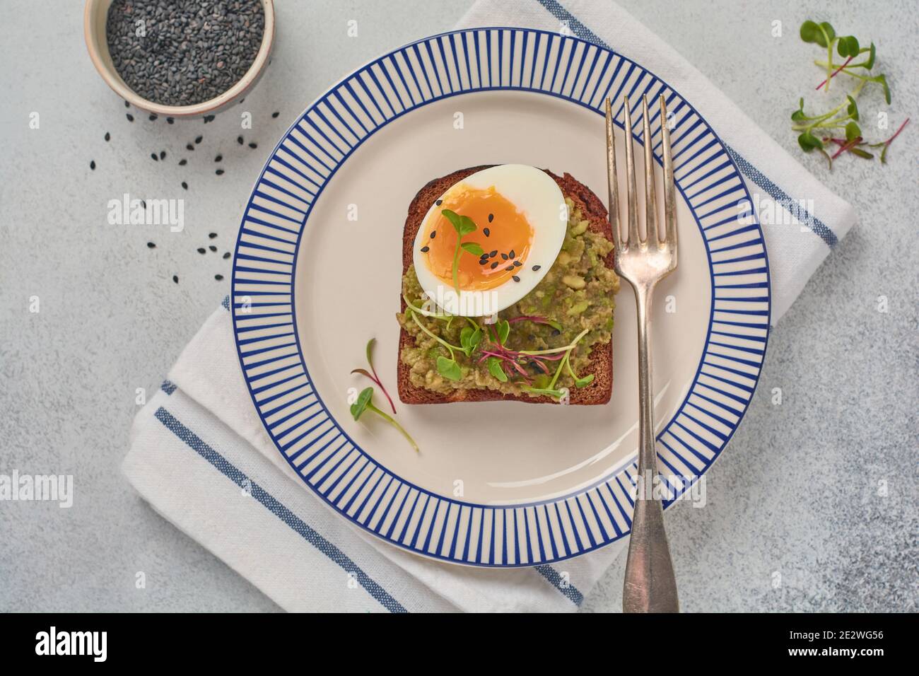 Un sano sandwich con avocado, uova e micrograni su un piatto da portata per la colazione. Concetto dietetico di nutrizione sana. Vista dall'alto. Foto Stock