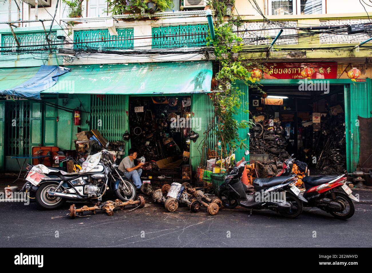 L'uomo siede nel negozio di riparazione automobilistica a Talat noi di Bangkok Quartiere Foto Stock