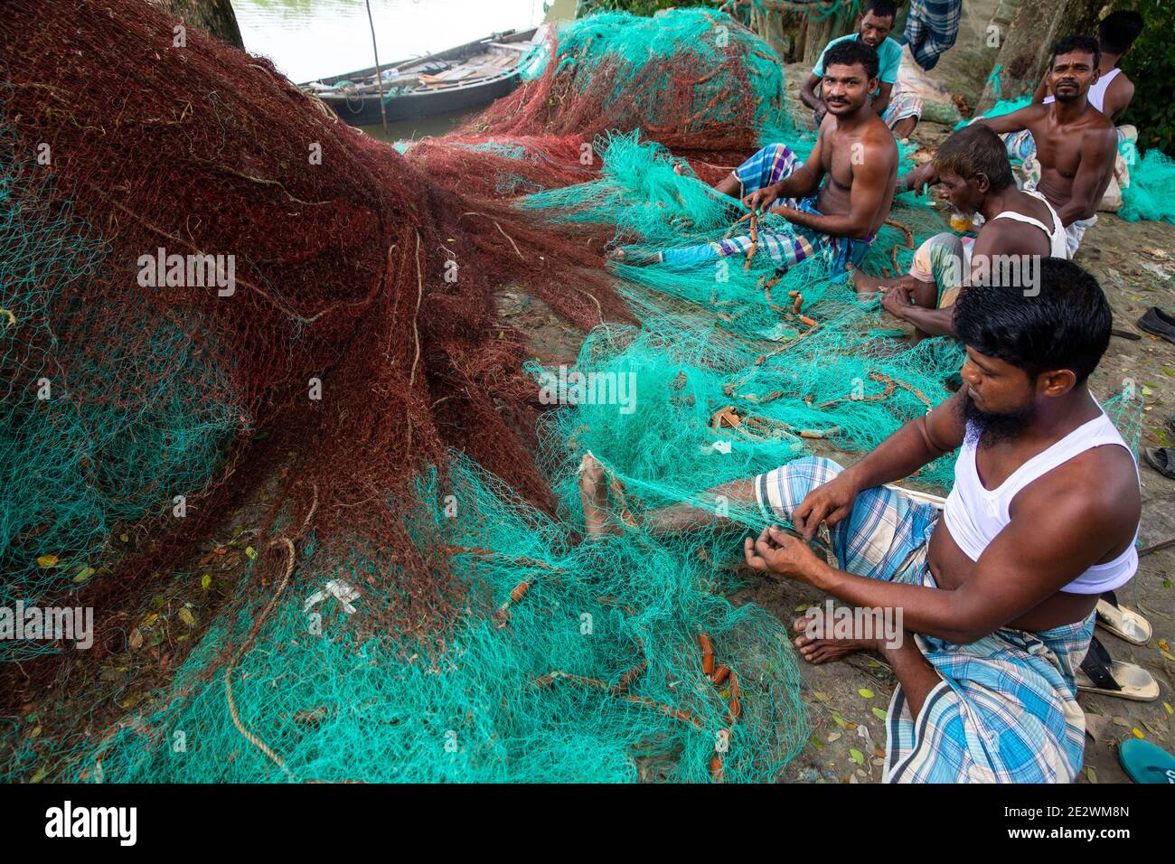 Pescatori che riparano le reti in un villaggio di pescatori sulla riva del fiume Meghna, Chandpur, bangladesh Foto Stock