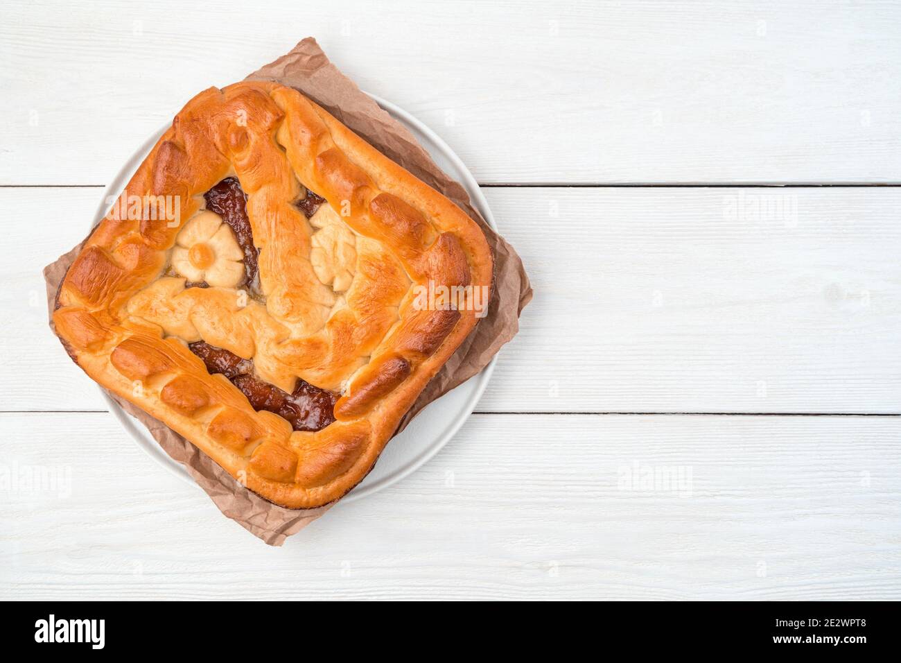 Torta fatta in casa con ripieno di mela su un piatto piatto con carta kraft su uno sfondo chiaro. Foto Stock