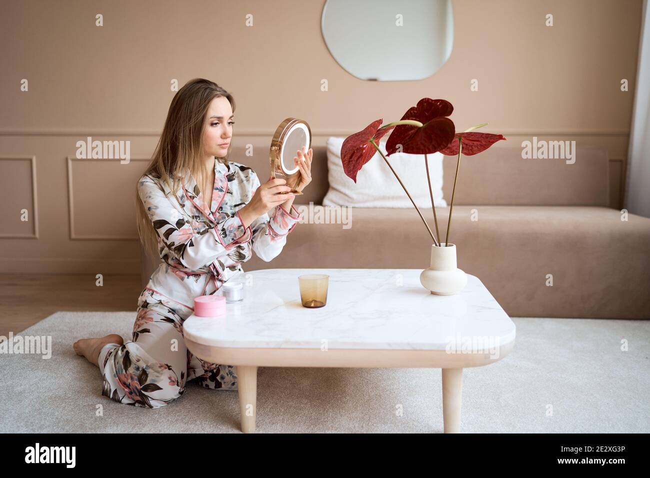 Donna attraente in pigiama che applica la crema del viso. Giovane donna attraente in pajama applicando crema idratante sul viso. Fresco dal mattino Foto Stock