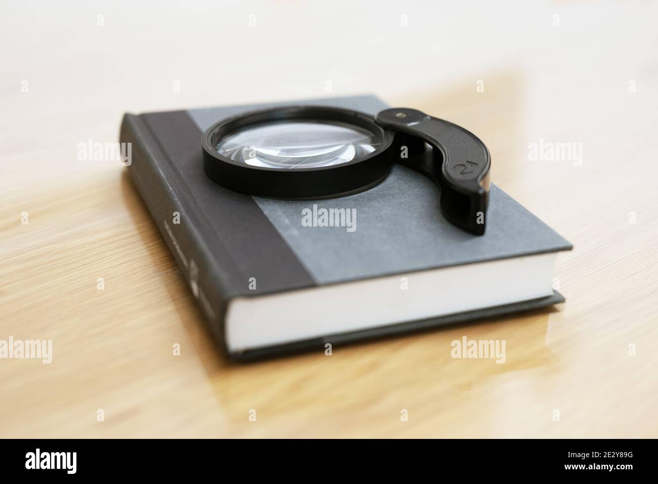 Una vecchia lente d'ingrandimento si trova sul libro sul tavolo di legno Foto Stock