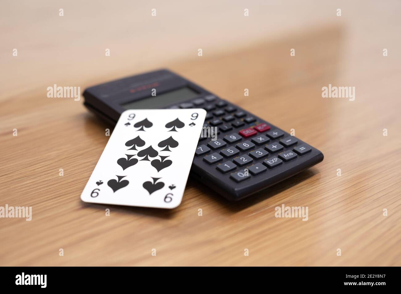 Calcolatrice e carta da gioco nera spade nove su tavolo di legno Foto Stock