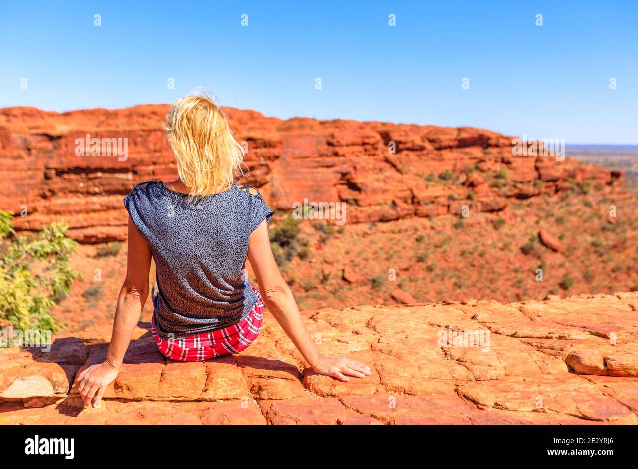 Donna caucasica che guarda vedute panoramiche del Kings Canyon nel Parco Nazionale di Watarrka, il Centro Rosso Australiano. I turisti si rilassano durante la passeggiata Rim a bordo Foto Stock