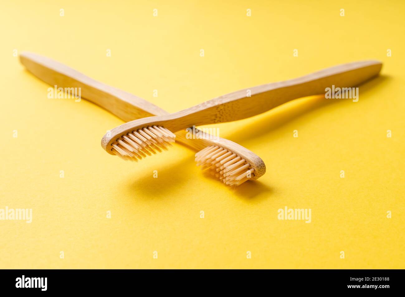 Spazzolini da denti organici di bambù per l'igiene dentale su sfondo giallo alla moda - materiale biodegradabile ecologico privo di rifiuti di plastica Foto Stock