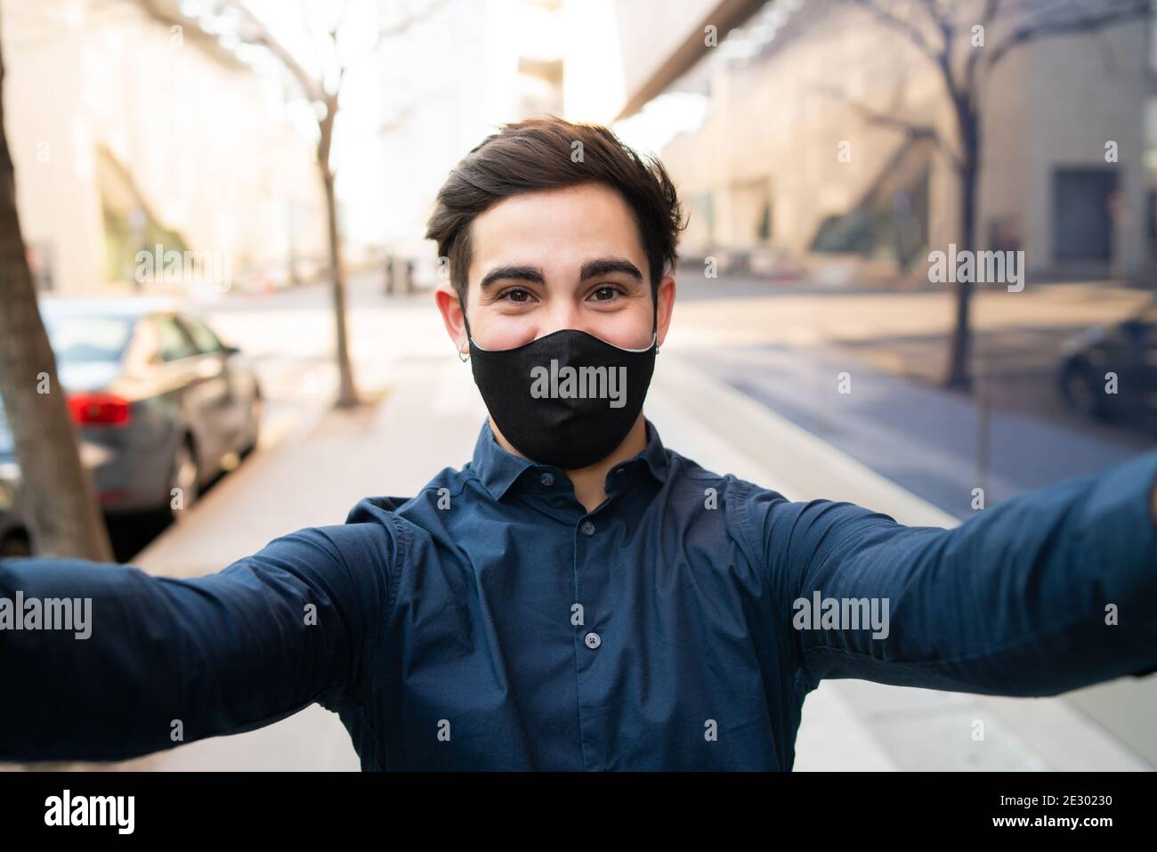 Ritratto di giovane uomo che prende un selfie all'aperto. Foto Stock